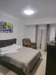 a bedroom with a bed and a chair at New Airport Apartment in Sibiu