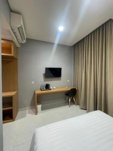 a bedroom with a bed and a desk with a television at Agiva Hotel in Kurinci