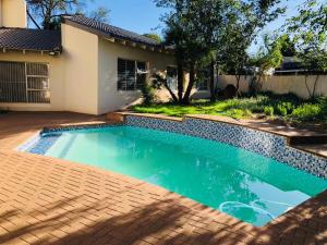 a swimming pool in front of a house at Twin Power Guesthouse in Bloemfontein