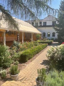 a house with a garden with flowers and a walkway at Złote Runo - Kameralny hotelik & Restauracja in Karolina