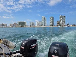a boat in the water with a city in the background at Beautiful Ocean View Apt Salinas Malecon Pier in Salinas