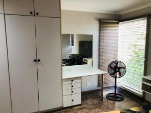 a kitchen with a desk and a fan next to a window at Twin Power Guesthouse in Bloemfontein