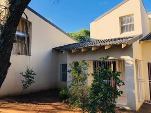 a white house with a tree in front of it at Twin Power Guesthouse in Bloemfontein