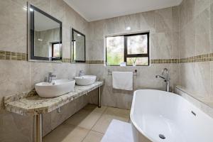 ein Badezimmer mit zwei Waschbecken, einer Badewanne und Spiegeln in der Unterkunft Botleng Guest House in Maseru + 62 Fotos
