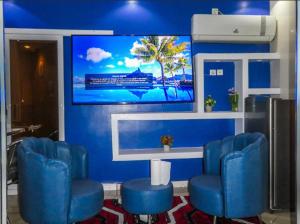 a waiting room with blue chairs and a large screen at Hotel Residence Ami Bamba in Sali Nianiaral