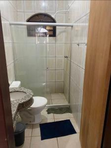 a small bathroom with a toilet and a shower at Praia do fort in Camacari +4 photos