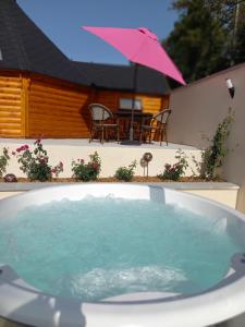 a hot tub in front of a house with a pink umbrella at Lodge Mon Petit Lapin in Montgon