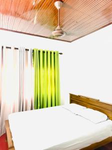 a bedroom with a bed with a green curtain at S70 Villa in Dickwella
