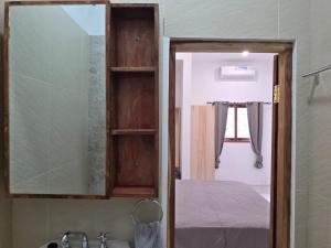 a bathroom with a mirror over a sink and a bed at Apartamentos de Metiaut in Dili