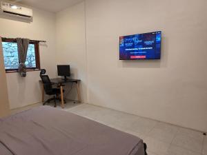 a room with a bed and a tv on the wall at Apartamentos de Metiaut in Dili