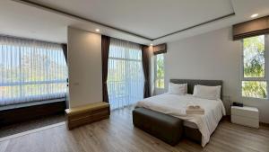 a bedroom with a bed and two large windows at Baan Suan Khun Ta and Golf Resort in Ubon Ratchathani +170 photos