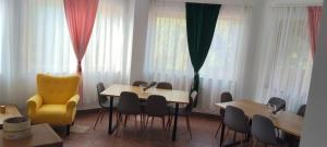a dining room with tables and chairs and windows at Pensiunea Patru Brazi in Muntele Cacovei