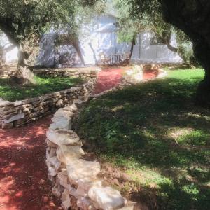 a stone wall in front of a house with a tree at Barreira beachfront Tents 9 in Verga Kalamata