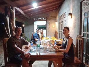 a group of people sitting around a wooden table at Wilpattu Buma Lodge in Pahala Maragahawewa