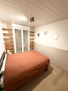 a bedroom with a bed and a window and shelves at L' Escapade Pannessac premier étage in Le Puy-en-Velay
