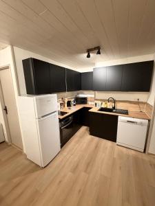an empty kitchen with white appliances and black cabinets at L' Escapade Pannessac premier étage in Le Puy-en-Velay +2 photos