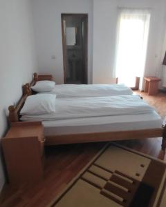 a large bed in a room with a wooden floor at Pensiunea Patru Brazi in Muntele Cacovei
