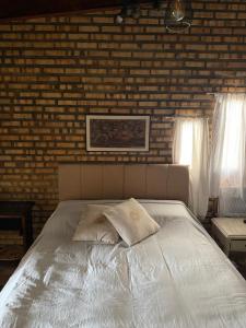 a bedroom with a white bed with a brick wall at Incanto in Niterói