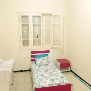 a small bedroom with a bed and a window at Chez Naceur Suite in Tozeur
