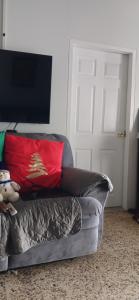 a grey couch with a red pillow and a television at Maria's Sanctuary in San Juan