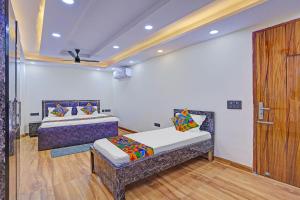 a room with two beds and a wooden door at FabHotel Havenora - Nr Maharani Bagh in New Delhi