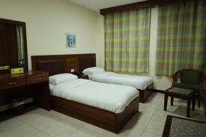 a room with two beds and a desk and a chair at Badan Suites & Hotel in Amman +12 photos