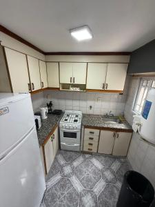 a small kitchen with a stove and a refrigerator at Duplex 4 con cochera privada y parrilla in San Clemente del Tuyú +10 photos