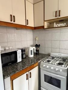 a kitchen with a stove and a microwave at Duplex 4 con cochera privada y parrilla in San Clemente del Tuyú