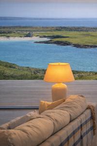 a lamp sitting on a couch with a view of the ocean at Luxury Glass Villa with Hot Tub & Sea Views - Connemara in Roundstone