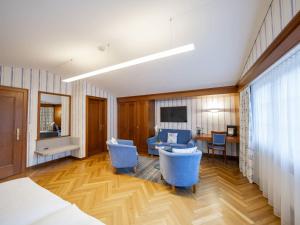 a room with blue chairs and a bed and a desk at Hotel Hecht in Appenzell