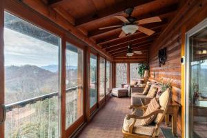 a screened in porch with chairs and a ceiling fan at Alpine Vista in Blowing Rock
