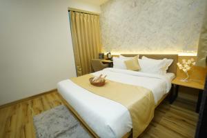 a hotel room with a large bed and a table at Hotel Anugya in Indore