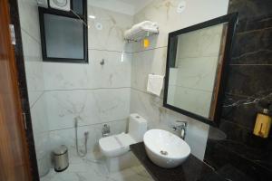 a bathroom with a sink and a toilet and a mirror at Hotel Anugya in Indore +10 photos