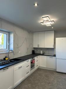 a kitchen with white cabinets and a white refrigerator at Biebrzańska Dolina 2 in Goniadz