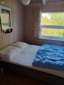 a bed in a room with a window at Beautiful cottage on a large natural plot in Ålbæk