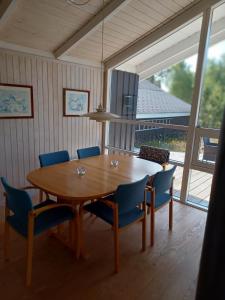 a dining room with a wooden table and blue chairs at Beautiful cottage on a large natural plot in Ålbæk