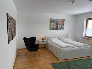 a white bedroom with a bed and a chair at Ferienwohnung Madera Campesina in Hunderdorf