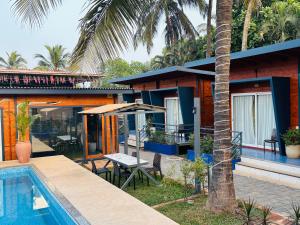 a house with a swimming pool next to a resort at Oyster Bay Beach Resort in Anjuna