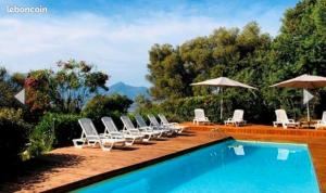 a group of chairs and umbrellas next to a swimming pool at Bungalow le Sartène in Lumio