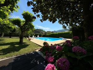 a garden with a swimming pool and flowers at Velo Ariege Pyrenees in La Bastide-de-Sérou
