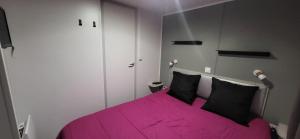 a bedroom with a pink bed with black pillows at Bungalow le Sartène in Lumio
