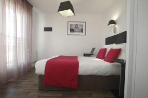 sypialnia z dużym łóżkiem z czerwonymi poduszkami w obiekcie Odalys City Paris Levallois w mieście Levallois-Perret