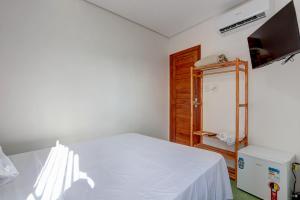a bedroom with a white bed and a refrigerator at Recanto Fiel in Itacaré