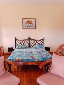 a bedroom with a bed with a blue comforter and two chairs at Greengardenlodge in Nosy Be +16 photos