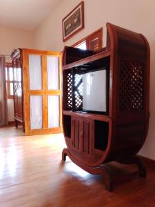 a tv in a wooden entertainment center in a living room at Greengardenlodge in Nosy Be
