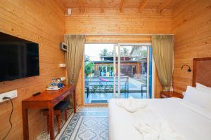 a bedroom with a bed and a desk and a television at Oyster Bay Beach Resort in Anjuna