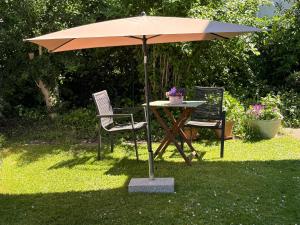 a table and two chairs under an umbrella at Apartment im Gründle in Birkenfeld