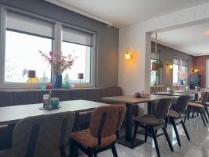 a restaurant with tables and chairs and windows at Berghotel Hohegeiß in Hohegeiß