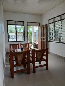a dining room with a table and chairs and windows at Villa Rosita - Apo Island in Dauin