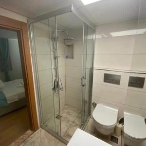 a bathroom with a toilet and a glass shower at Sığacıksenkonukevi in Siğacık